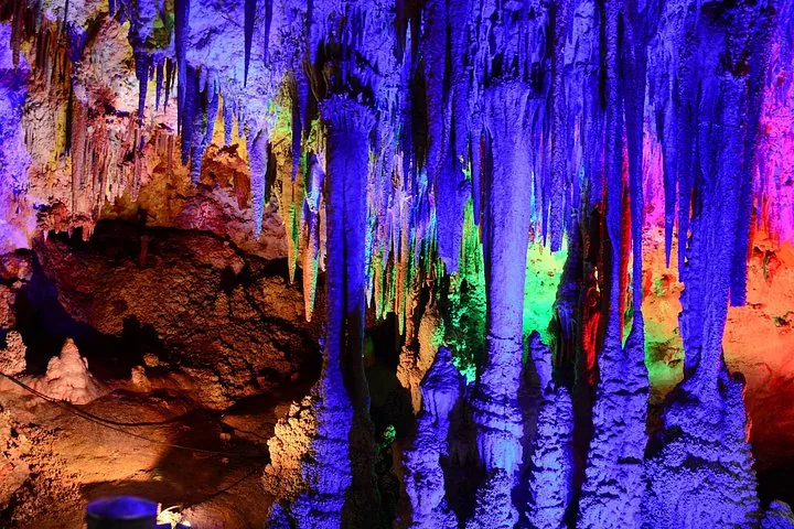 Leuchtend farbige Stalaktiten und Stalagmiten in einer beleuchteten Höhle