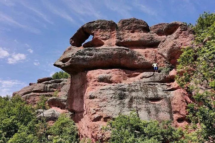 Person standing on a large red rock formation at Belogradchik